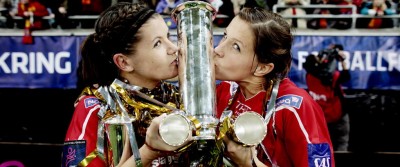 Two female athletes kissing a phallic trophy